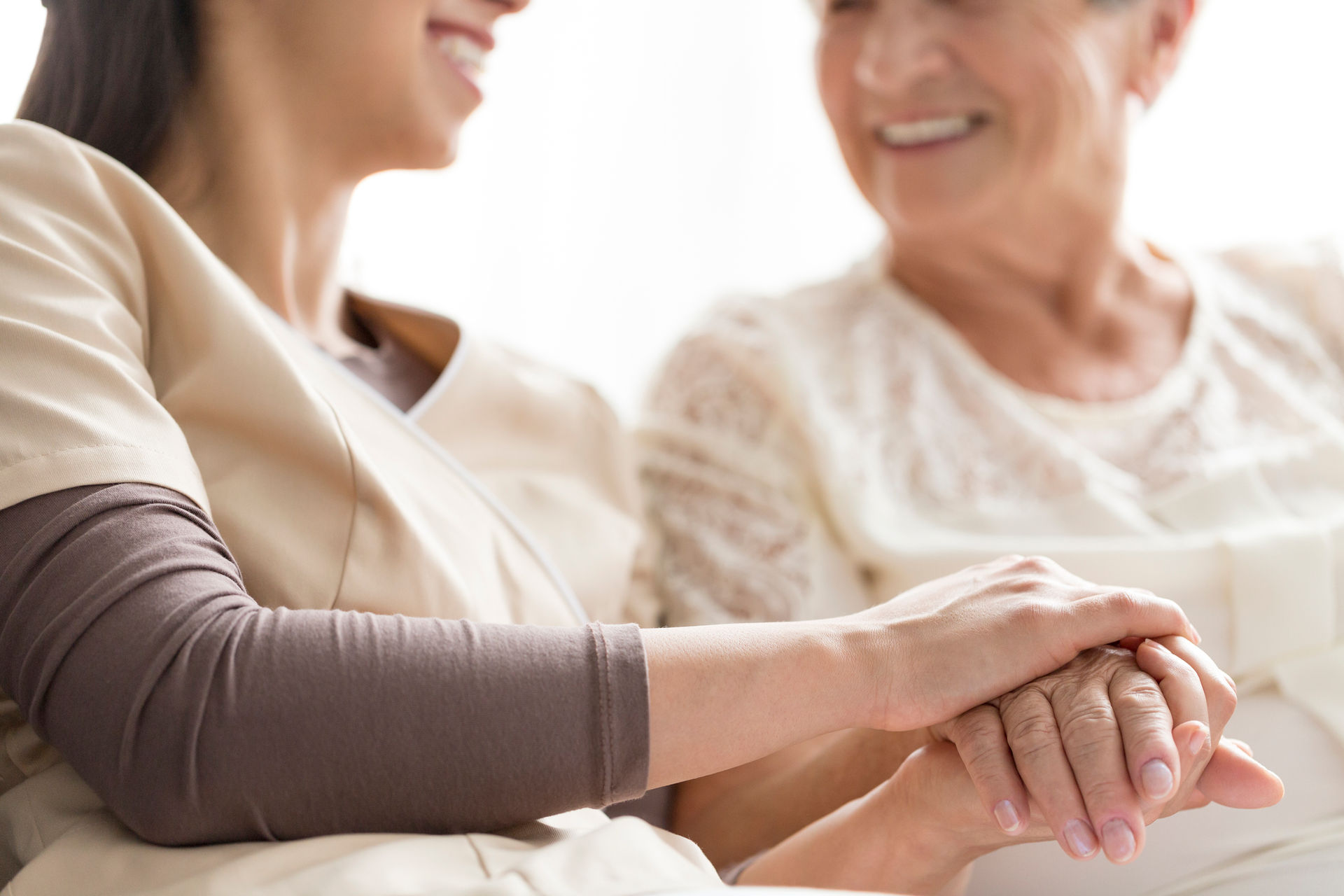 A caregiver holding the hand of an elderly patient